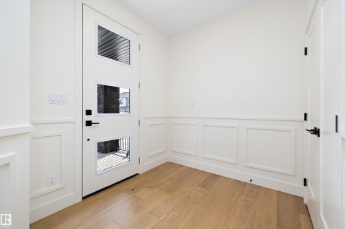 Doorway to outside with wood finished floors, a decorative wall, and a wainscoted wall - 6871 Knox Loop Sw, Edmonton, AB - Indoor Photo Showing Other Room