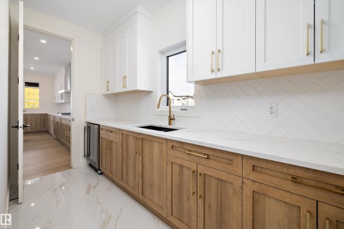 Kitchen featuring dual tone cabinetry, light stone countertops, light marble finish flooring, backsplash, and recessed lighting - 6871 Knox Loop Sw, Edmonton, AB - Indoor Photo Showing Kitchen With Double Sink