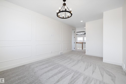 Unfurnished dining area featuring a decorative wall, light carpet, and a chandelier - 6871 Knox Loop Sw, Edmonton, AB - Indoor Photo Showing Other Room