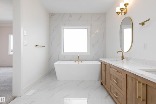 Bathroom featuring double vanity, light marble finish flooring, and a freestanding tub - 6871 Knox Loop Sw, Edmonton, AB - Indoor Photo Showing Bathroom