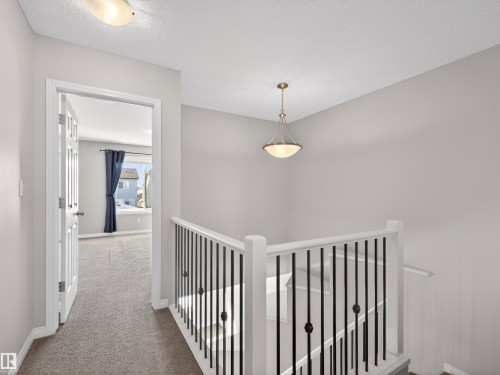 Hall featuring carpet floors, a textured ceiling, and an upstairs landing - 1267 Chappelle Boulevard, Edmonton, AB - Indoor Photo Showing Other Room