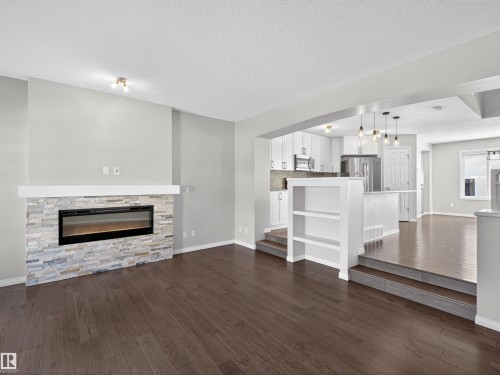 Living room with a fireplace, dark wood-style floors, and a textured ceiling - 1267 Chappelle Boulevard, Edmonton, AB - Indoor Photo Showing Living Room With Fireplace