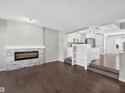 Living room with a fireplace, dark wood-style floors, and a textured ceiling - 