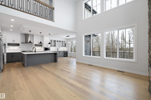 Dual tone kitchen with a kitchen island with sink, hanging light fixtures, light wood-style flooring, glass insert cabinets, and dual tone cabinets - 718 Elderberry Close Nw, Edmonton, AB - Indoor Photo Showing Kitchen With Upgraded Kitchen