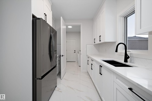 Kitchen with freestanding refrigerator, white cabinets, light stone countertops, and light marble finish floors - 718 Elderberry Close Nw, Edmonton, AB - Indoor Photo Showing Kitchen With Double Sink With Upgraded Kitchen