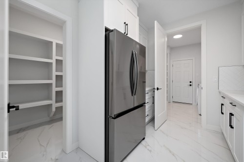 Kitchen with freestanding refrigerator, white cabinets, light marble finish flooring, and light stone countertops - 718 Elderberry Close Nw, Edmonton, AB - Indoor