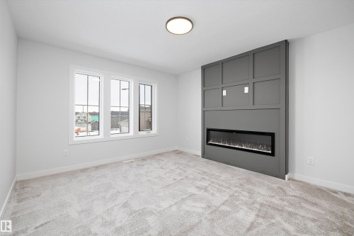 Unfurnished living room with light colored carpet and a fireplace - 718 Elderberry Close Nw, Edmonton, AB - Indoor Photo Showing Other Room With Fireplace