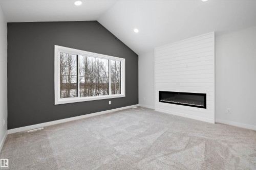 Unfurnished living room featuring a large fireplace, light carpet, and recessed lighting - 718 Elderberry Close Nw, Edmonton, AB - Indoor Photo Showing Living Room With Fireplace
