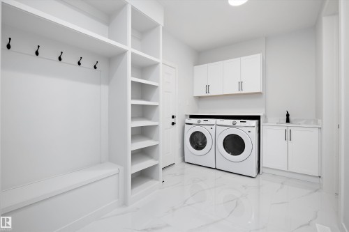 Laundry room with cabinet space, separate washer and dryer, and light marble finish flooring - 718 Elderberry Close Nw, Edmonton, AB - Indoor Photo Showing Laundry Room