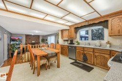 Kitchen featuring light countertops, wood finish cabinetry, dishwasher, electric range oven, and healthy amount of natural light - 
