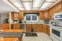 Kitchen with white appliances, wood finish cabinetry, and light tile patterned flooring - 