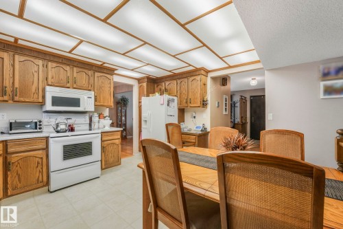 Kitchen with white appliances, wood finish cabinetry, light countertops, and light flooring - 15909 112 B Street Nw, Edmonton, AB - Indoor Photo Showing Kitchen