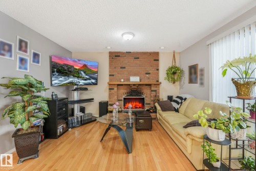 Living area featuring hardwood / wood-style floors, a fireplace, and a textured ceiling - 15909 112 B Street Nw, Edmonton, AB - Indoor With Fireplace