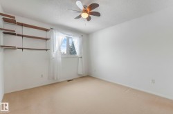 Empty room with light colored carpet, a ceiling fan, and a textured ceiling - 
