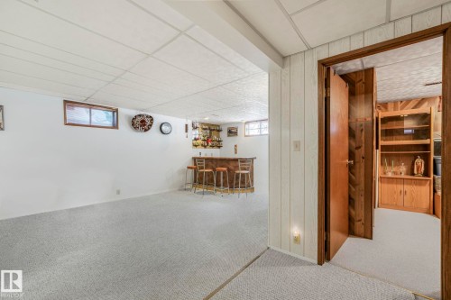 Basement with a bar, carpet flooring, a drop ceiling, and wood walls - 15909 112 B Street Nw, Edmonton, AB - Indoor