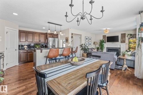 Dining area with hanging lights, a fireplace, and dark wood finished floors - 10415 94 Street, Morinville, AB - Indoor Photo Showing Other Room With Fireplace