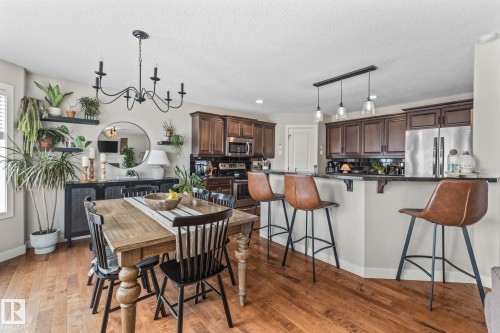 Dining area featuring a chandelier, dark wood finished floors, and a textured ceiling - 10415 94 Street, Morinville, AB - Indoor
