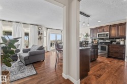 Kitchen with stainless steel appliances, open floor plan, a textured ceiling, dark wood finished floors, and hanging light fixtures - 