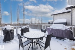 Snow covered patio with a grill, a deck, outdoor dining area, and a fenced backyard - 