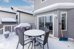 Snow covered patio featuring outdoor dining space, a wooden deck, and grilling area - 