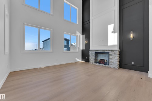 Unfurnished living room with a high ceiling, light wood finished floors, and a fireplace - 95 Eldridge Point(E), St. Albert, AB - Indoor With Fireplace