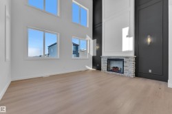 Unfurnished living room with a high ceiling, light wood finished floors, and a fireplace - 