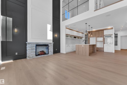 Unfurnished living room featuring a stone fireplace, recessed lighting, light wood-type flooring, and a high ceiling - 95 Eldridge Point(E), St. Albert, AB - Indoor With Fireplace