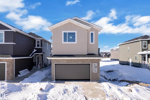 View of front of house with an attached garage, a residential view, and stone siding - 95 Eldridge Point(E), St. Albert, AB - Outdoor
