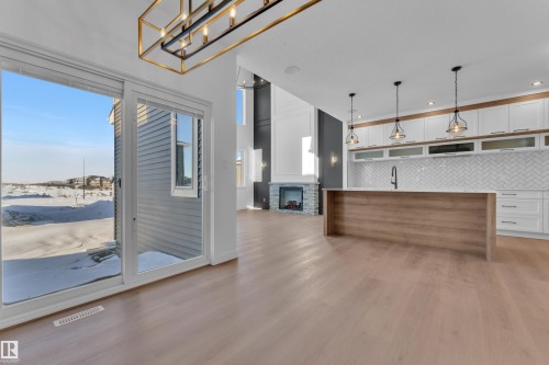 Two tone kitchen featuring two tone cabinetry, light wood-style flooring, open floor plan, a stone fireplace, and open shelves - 95 Eldridge Point(E), St. Albert, AB - Indoor