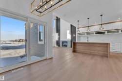 Two tone kitchen featuring two tone cabinetry, light wood-style flooring, open floor plan, a stone fireplace, and open shelves - 