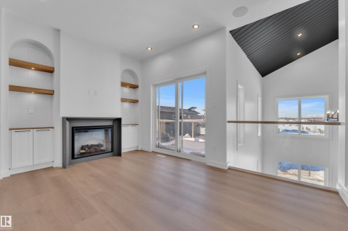 Unfurnished living room with built in features, a glass covered fireplace, recessed lighting, light wood-style floors, and vaulted ceiling - 95 Eldridge Point(E), St. Albert, AB - Indoor With Fireplace