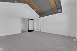 Empty room with light colored carpet, lofted ceiling, and recessed lighting - 