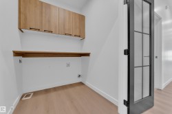 Laundry room with light wood-style floors and cabinet space - 