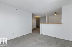 Empty room featuring carpet floors, a textured ceiling, and hanging lights - 