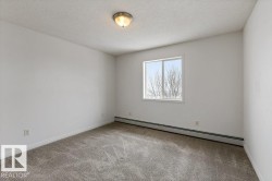 Empty room featuring baseboard heating, a textured ceiling, and light colored carpet - 