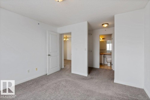 Unfurnished bedroom featuring light colored carpet, a textured ceiling, and ensuite bathroom - 403 14708 50 Street, Edmonton, AB - Indoor