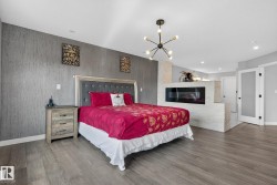Bedroom with wood finished floors, a glass covered fireplace, and suspended lighting - 