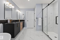 Full bathroom with double vanity, a marble finish shower, and light marble finish flooring - 