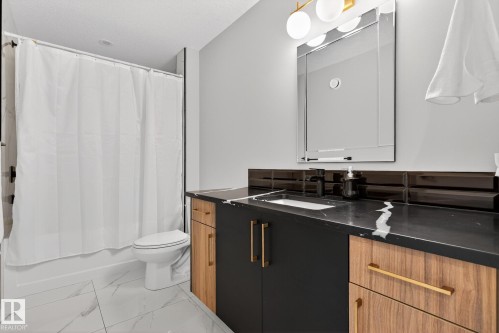 Bathroom featuring vanity, shower / tub combo, and marble look tiles - 1027 150 Avenue, Edmonton, AB - Indoor Photo Showing Bathroom