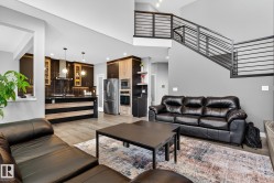Living room with light wood-style floors, a high ceiling, and recessed lighting - 