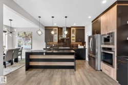 Kitchen featuring a center island with sink, stainless steel appliances, modern cabinets, and dark stone counters - 