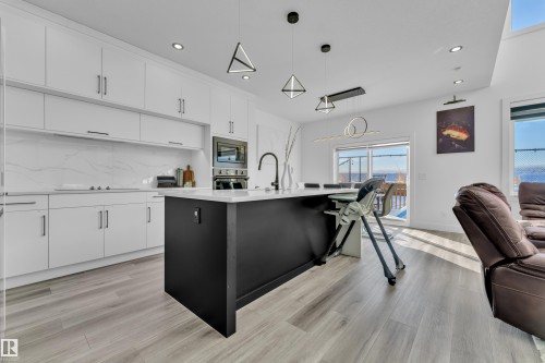 Two tone kitchen featuring open floor plan, a center island with sink, pendant lighting, two tone cabinetry, and light wood-style floors - 316 42 Street, Edmonton, AB - Indoor Photo Showing Kitchen With Upgraded Kitchen