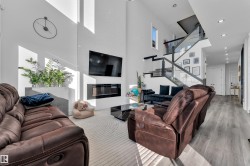 Living area with a glass covered fireplace, a high ceiling, wood finished floors, recessed lighting, and plenty of natural light - 