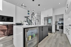 Bar featuring wine cooler, two tone color scheme, modern cabinets, stainless steel appliances, and pendant lighting - 