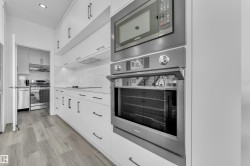 Kitchen featuring stainless steel appliances, light wood-style flooring, white cabinets, recessed lighting, and decorative backsplash - 