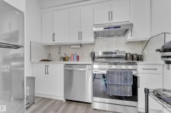 Kitchen with stainless steel appliances, white cabinets, and decorative backsplash - 