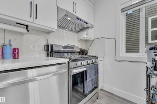 Kitchen with stainless steel appliances, light stone countertops, white cabinets, and light wood finished floors - 316 42 Street, Edmonton, AB - Indoor Photo Showing Kitchen