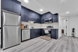 Kitchen with stainless steel appliances, light wood finished floors, modern cabinets, recessed lighting, and backsplash - 