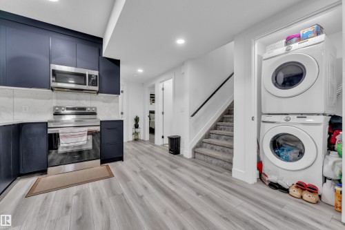 Kitchen with modern cabinets, stainless steel appliances, stacked washer / drying machine, light wood-style floors, and recessed lighting - 316 42 Street, Edmonton, AB - Indoor Photo Showing Laundry Room