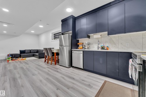 Kitchen with modern cabinets, stainless steel appliances, open floor plan, light wood finished floors, and recessed lighting - 316 42 Street, Edmonton, AB - Indoor Photo Showing Kitchen With Upgraded Kitchen